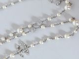 rosary necklace with cross and pearls on a white background