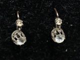 une paire de boucles d'oreilles en or ornées de cristaux transparents sur un fond noir