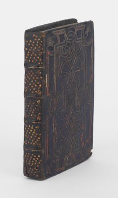 un vieux livre orné d'un motif décoratif, posé sur une surface blanche