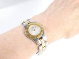 wrist shot of a woman ' s wrist with a gold and silver watch