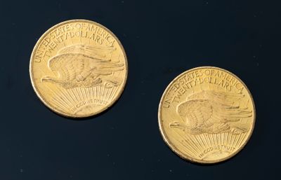 two gold coins sitting on top of a black surface next to each other