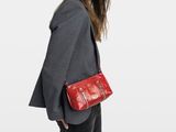 La femme marche avec un sac à main rouge et un chapeau noir.
