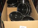 une caisse remplie de casseroles et de poêles posée par terre