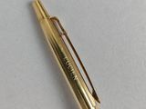 a close up of a gold pen on a white surface