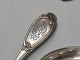 several silver spoons and spoon rest on a table with other silver spoons