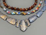 several different necklaces with different designs and colors on a table
