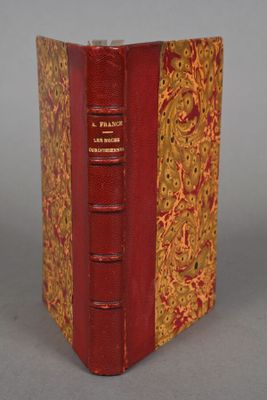 an old book with a red cover sitting on top of a table