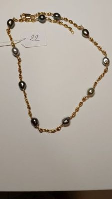 a close up of a gold chain bracelet with pearls on it