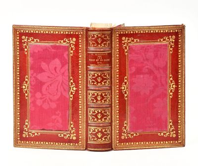 un livre rouge aux bords dorés et à la couverture rose