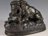 statue en bronze représentant un lion perché sur un rocher, tenant une souris dans la gueule