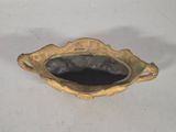 a gold plate with a black bowl inside of it