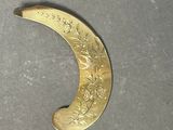 a gold crescent shaped object on a silver plate