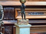 une statue représentant un garçon tenant un ballon, posée sur un socle