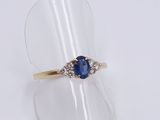 a close up of a blue sapphire and diamond ring on a clear ring holder