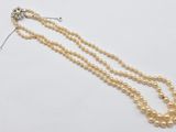 a close up of a necklace with pearls on a white surface