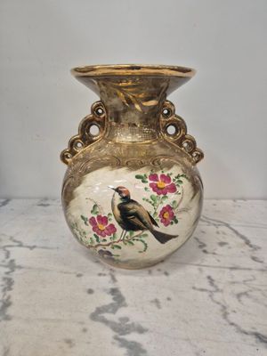 un vase sur lequel est peint un oiseau, posé sur une table