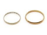 two gold and silver wedding rings on a white surface