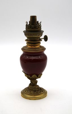 un vase rouge et doré posé sur une surface blanche