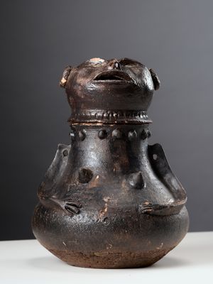 un vase noir posé sur une table, sur fond gris