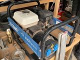 Quelqu'un travaille sur une machine dans un garage, où d'autres outils sont posés sur une étagère.