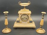 trois bougies et une horloge posées sur une table