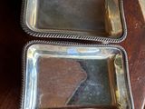 two silver trays sitting on top of a wooden table