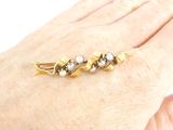 a woman ' s hand holding a gold ring with pearls on it
