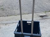 un panier en plastique noir muni d'une poignée, posé sur le trottoir