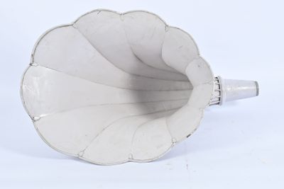 un vase blanc muni d'une anse argentée, posé sur une surface blanche