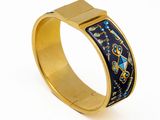 un gros plan sur un bracelet en or orné d'un motif bleu et jaune