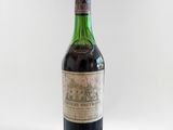 une vieille bouteille de vin posée sur une surface blanche