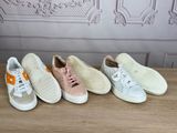 four pairs of sneakers are lined up on a wooden table