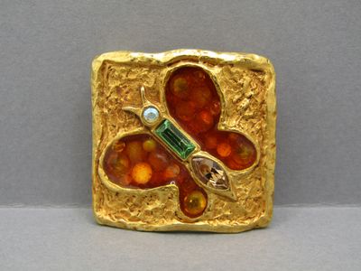 une image représentant une broche rouge et dorée ornée d'un papillon