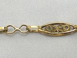 a close up of a gold bracelet on a white shirt