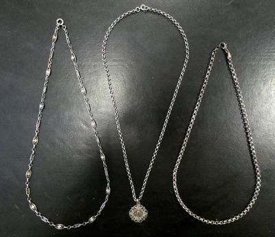 deux colliers en argent posés sur une surface noire avec un fond blanc