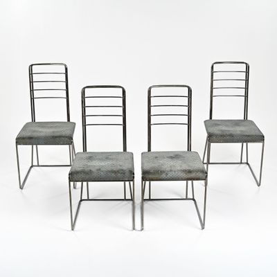 Quatre chaises en métal à l'assise rembourrée sont disposées devant un fond blanc.