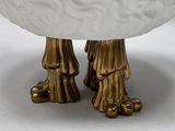 a close up of a white bowl with gold feet