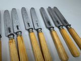 six knives are lined up in a row on a white surface
