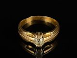 un gros plan d'une bague en or sertie d'un diamant sur un fond noir