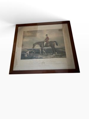 a framed picture of a man riding a horse and a dog