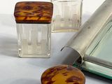 three small glass jars and a mirror on a table