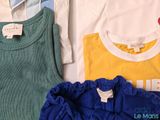 three baby clothes sitting on top of a white table next to each other