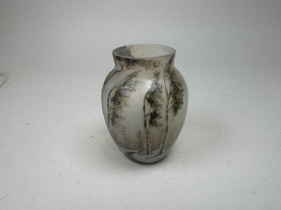 a white and black vase sitting on a white surface