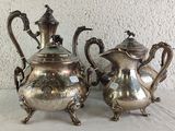 two silver teapots sitting on a table next to each other