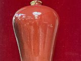 a red vase sitting on a table in front of a red wall