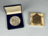 une photo représentant une médaille d'argent et une médaille d'argent dans un coffret