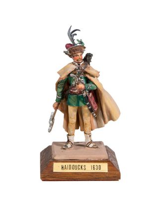 the figurine of a man with a hat and coat is standing on a wooden base