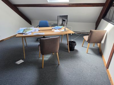 a desk with two chairs and a computer on it in a room