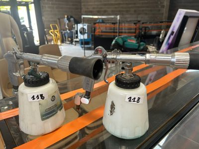 deux pistolets pulvérisateurs posés sur une table en verre
