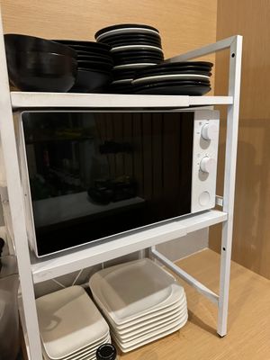 a microwave that is on top of a shelf with plates and bowls